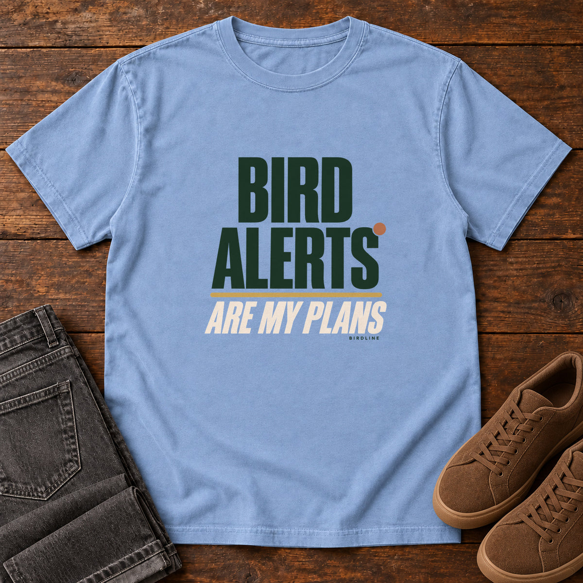 Washed Denim Bird Alerts Are My Plans T-Shirt with stacked green-and-cream lettering and an orange accent; front flat lay on wood.