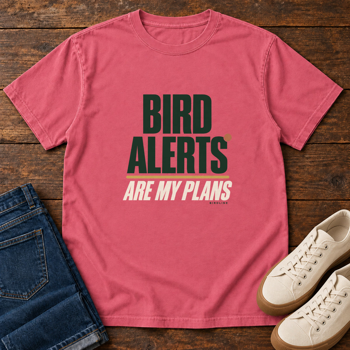 Watermelon Bird Alerts Are My Plans T-Shirt with stacked green-and-cream lettering and an orange accent; front flat lay on wood.
