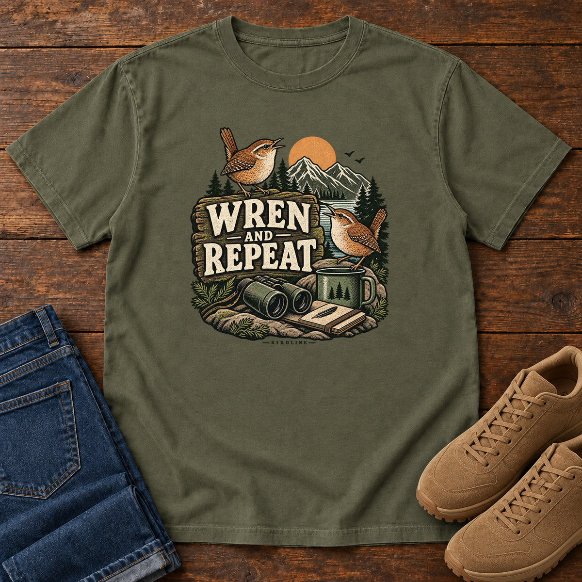 Sage Wren and Repeat T-Shirt with two small brown birds, binoculars and a camp mug around Wren and Repeat lettering, front flat lay on wood.