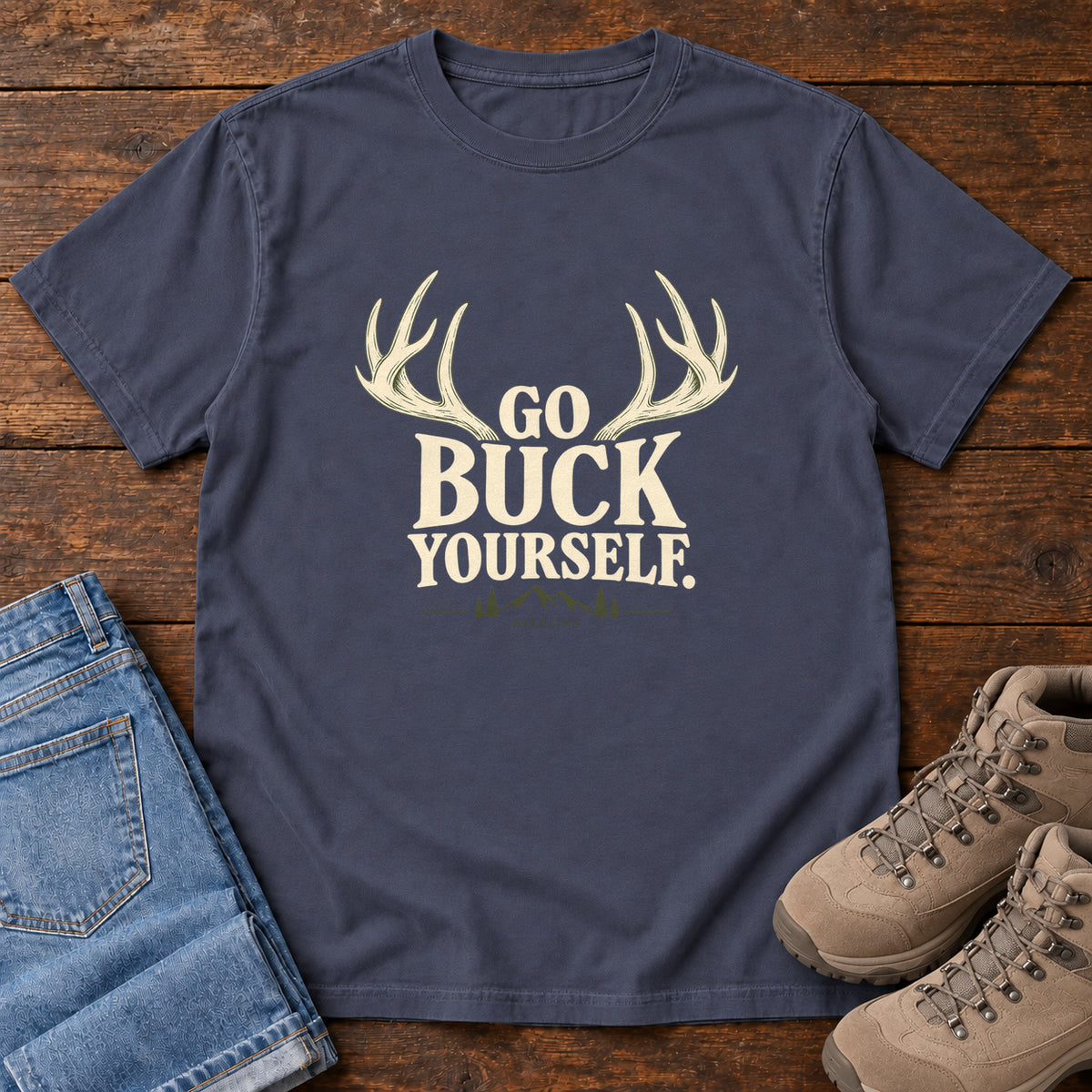 Navy Go Buck Yourself T-Shirt with cream deer antlers framing Go Buck Yourself lettering, front flat lay on wood.