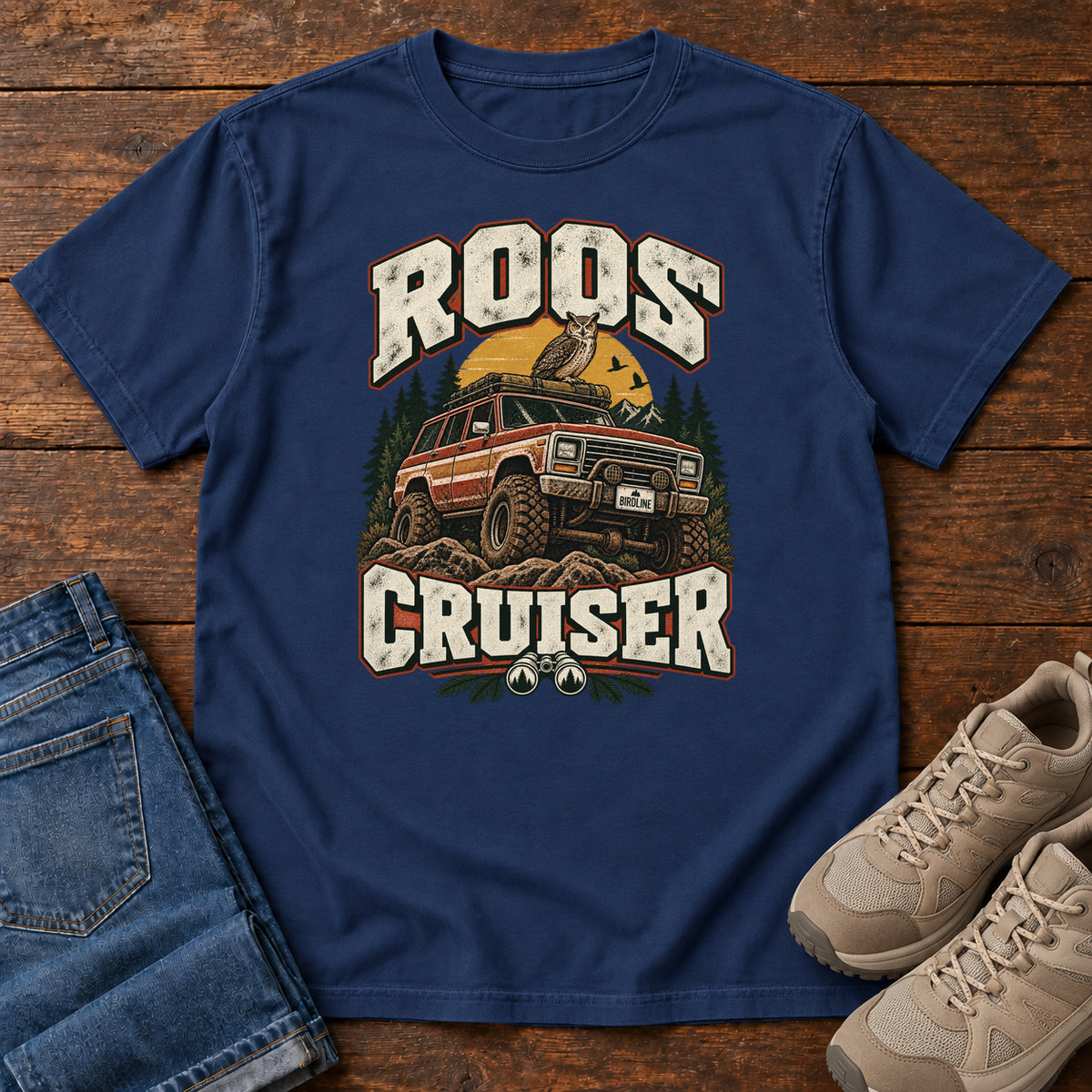 True Navy Roos Cruiser T-Shirt with a bird perched on an off-road vehicle between distressed cream Roos Cruiser lettering, front flat lay on wood.