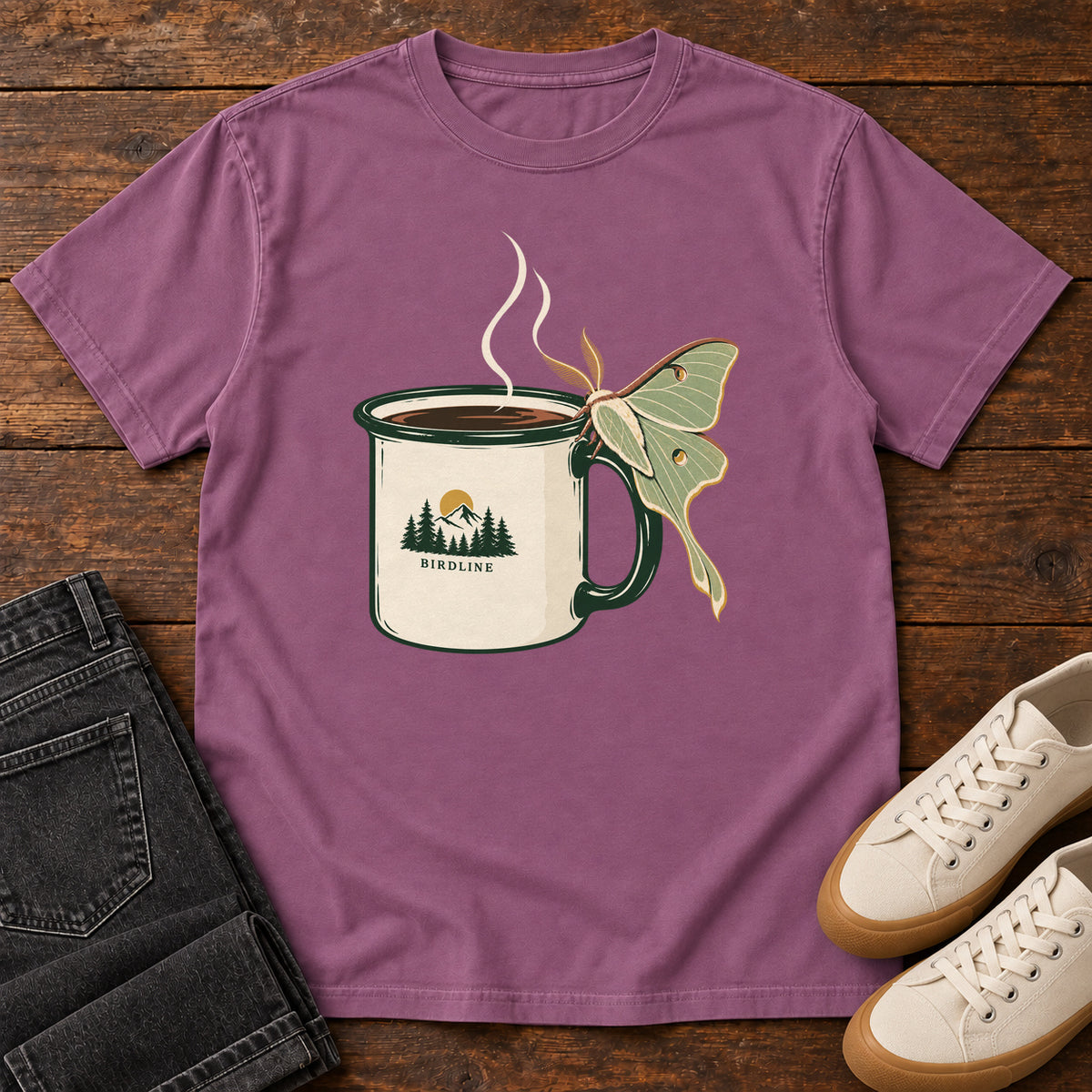 Berry Coffee and Luna Moth T-Shirt with a steaming cream camp mug with green trim and a pale green long-tailed moth; front flat lay on wood.