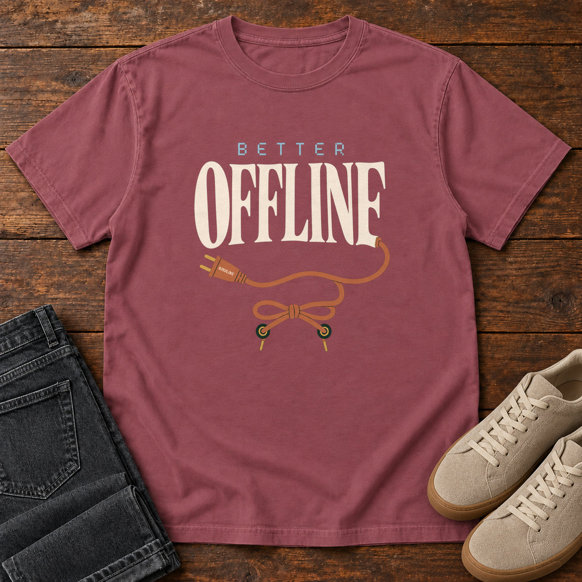 Brick Better Offline T-Shirt with cream Better Offline lettering and an orange unplugged cord; front flat lay on wood.