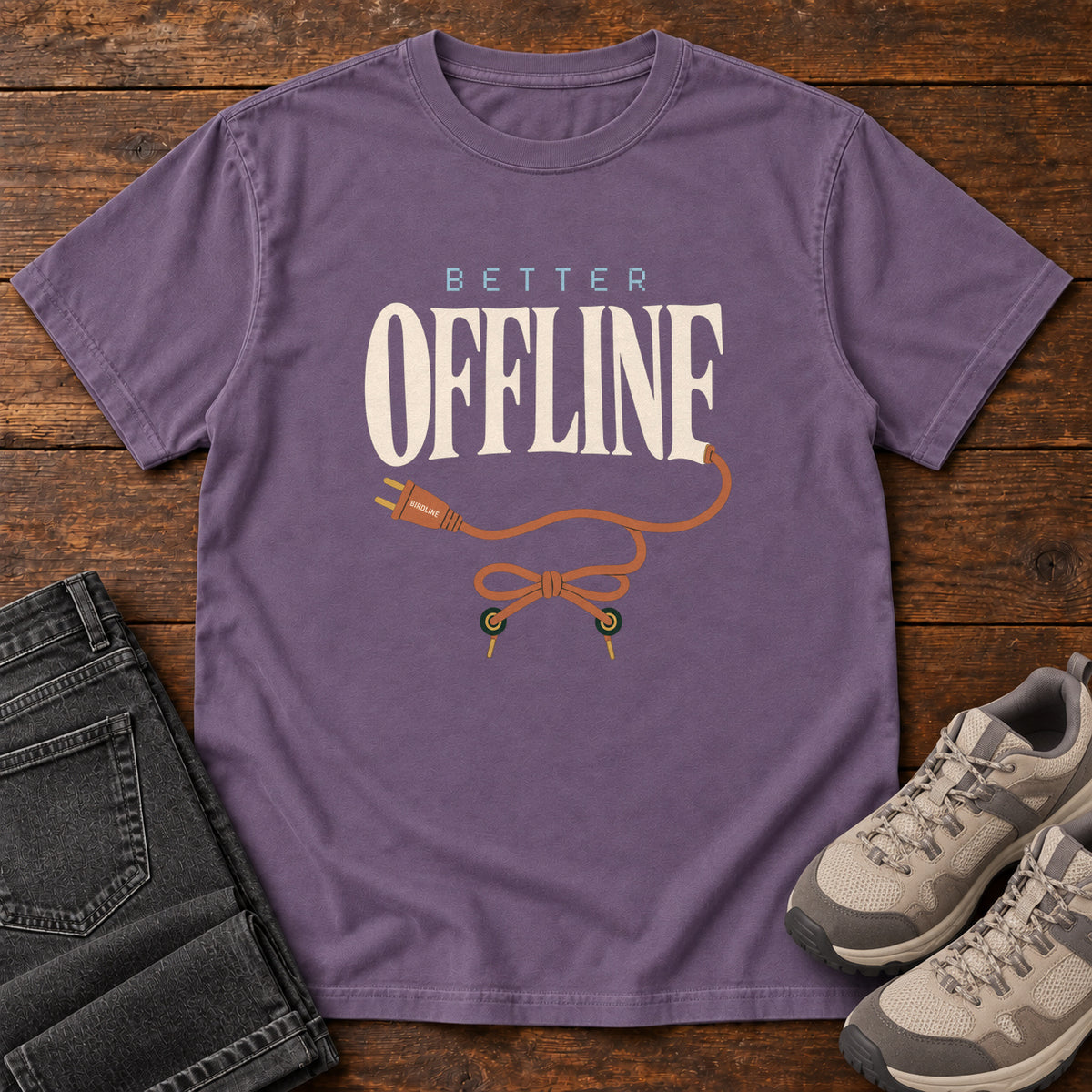 Grape Better Offline T-Shirt with cream Better Offline lettering and an orange unplugged cord; front flat lay on wood.