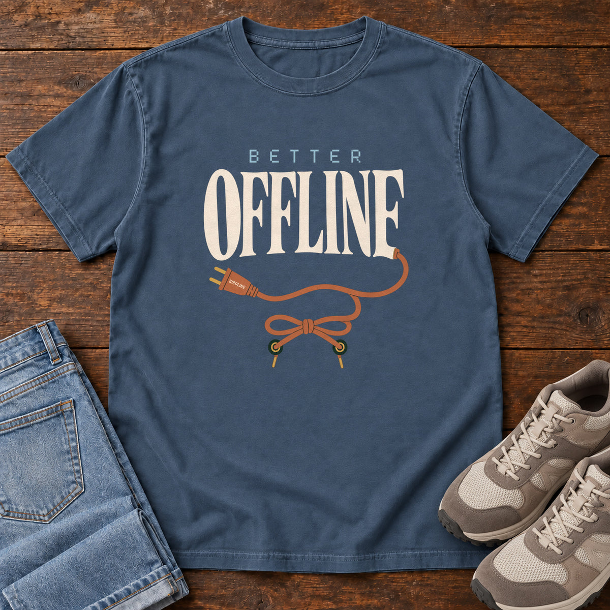 Midnight Better Offline T-Shirt with cream Better Offline lettering and an orange unplugged cord; front flat lay on wood.