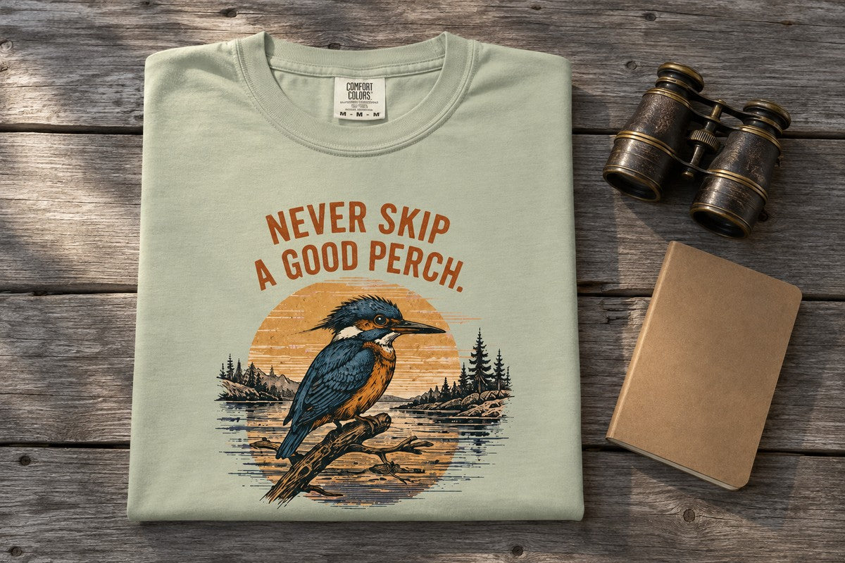 Folded Never Skip a Good Perch tee with binoculars and field notebook